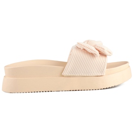 Zapatillas de mujer beige con lazo sobre suela gruesa.