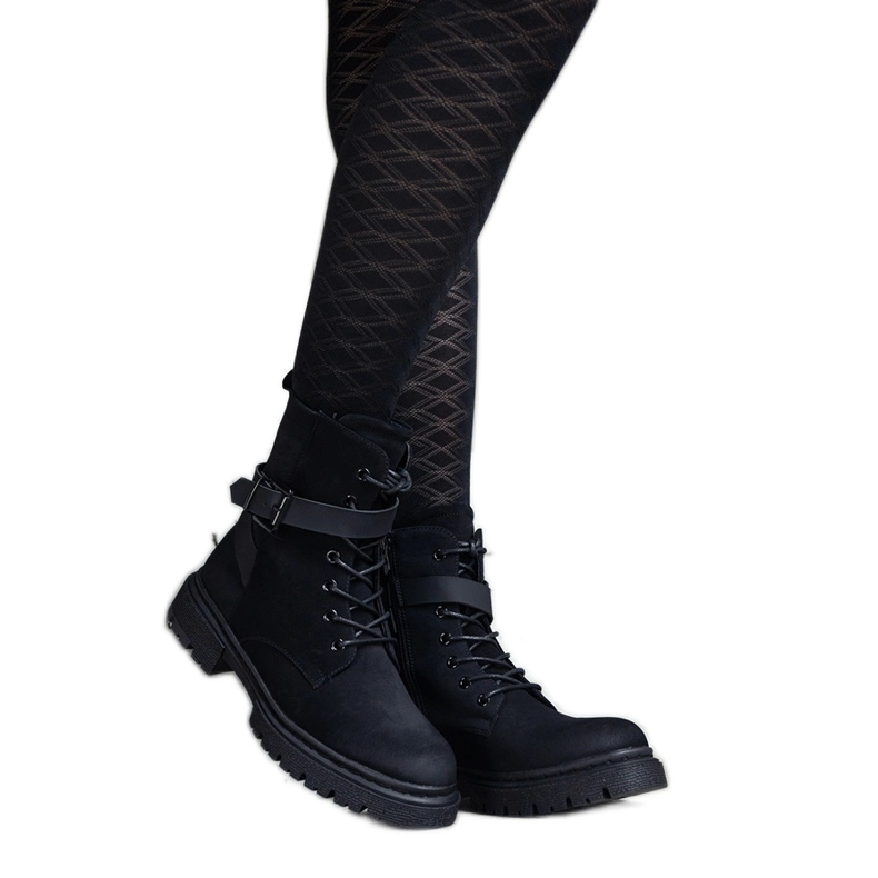 Botas de montaña con aislamiento negro con abrasiones y correa en las rodillas.