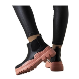 Botines negros sobre plataforma rosa.