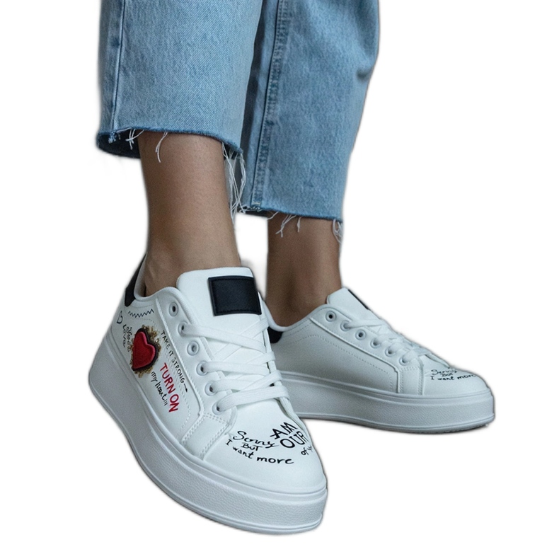 Zapatillas blancas decoradas con parche e inscripciones en la plataforma. blanco