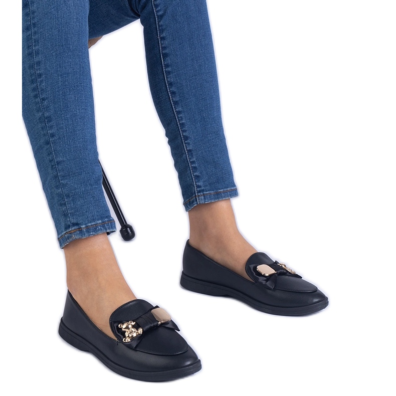 Mocasines negros decorados con un arco y un oso de peluche dorado