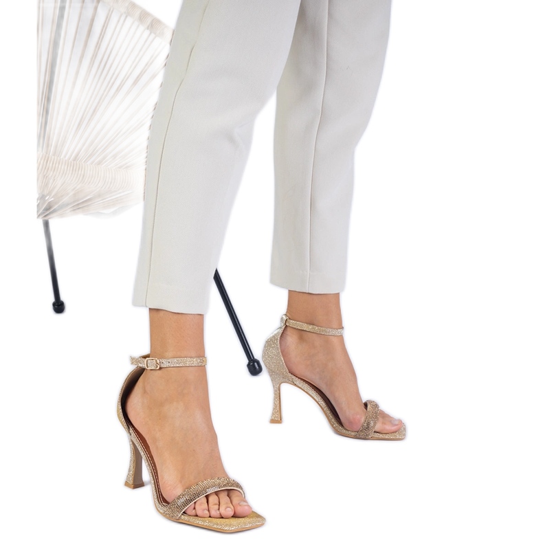 Sandalias doradas elegantes en un tacón alto decorado con circones dorado
