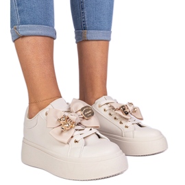 Zapatillas beige decoradas con un arco y un oso de peluche dorado Zapatillas beige decoradas con un arco y un oso de peluche dorado
