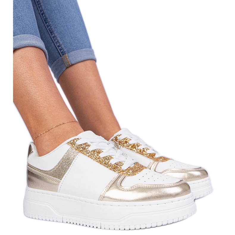 Zapatillas doradas para mujeres en una suela gruesa decorada con brillo dorado