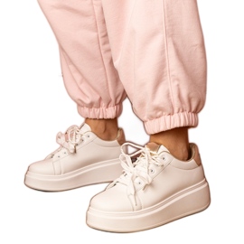 Zapatillas de deporte de deportes blancos y dorados en la plataforma