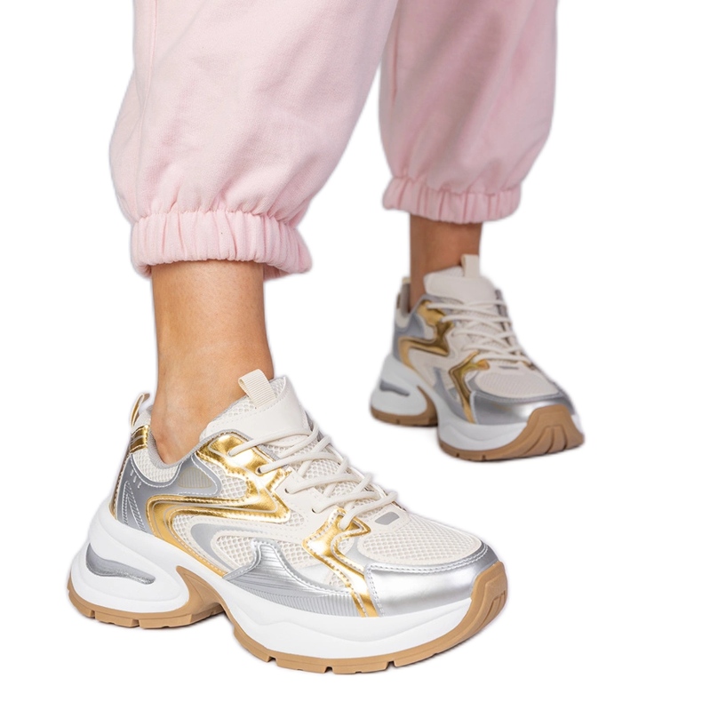 Zapatillas de deporte de deportes dorados en una suela gruesa