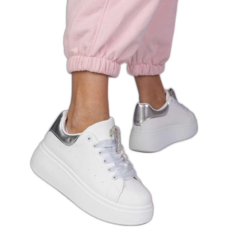 Zapatillas blancas con un inserto plateado y un alfiler con circones blanco
