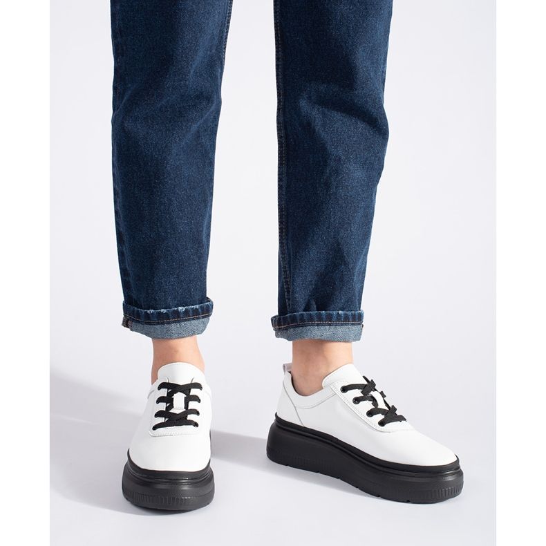 Zapatos blancos de cuero sobre una plataforma negra. 2